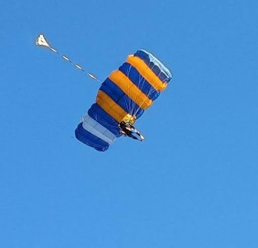 Skydiver floating gracefully in the air, viewed from the ground against a clear sky. This image captures the exhilaration of taking leaps, symbolizing the supportive role of a mentor in helping individuals flourish through life’s challenges and growth opportunities. Represents the journey of embracing courage and resilience with the guidance of an experienced mentor.